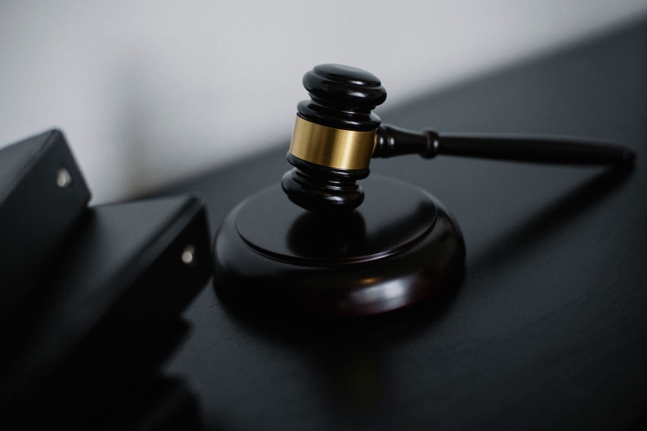 High angle of shiny wooden ceremonial mallet with golden detail placed on judge tale near documents folders